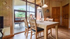 Un interior de madera con una mesa de comedor, sillas y un ventanal grande.