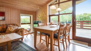 Un interior de madera con una mesa de comedor, sillas, un sofá y un televisor.