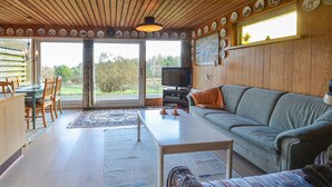A cozy living room with a sofa, a coffee table, a TV, and a dining area with chairs and a table.