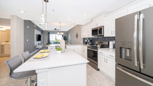 A modern kitchen with white cabinetry, stainless steel appliances, and a central island with seating.