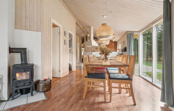 Enjoy meals around a spacious dining table surrounded by comfortable chairs, with a wood-burning stove and high ceiling.