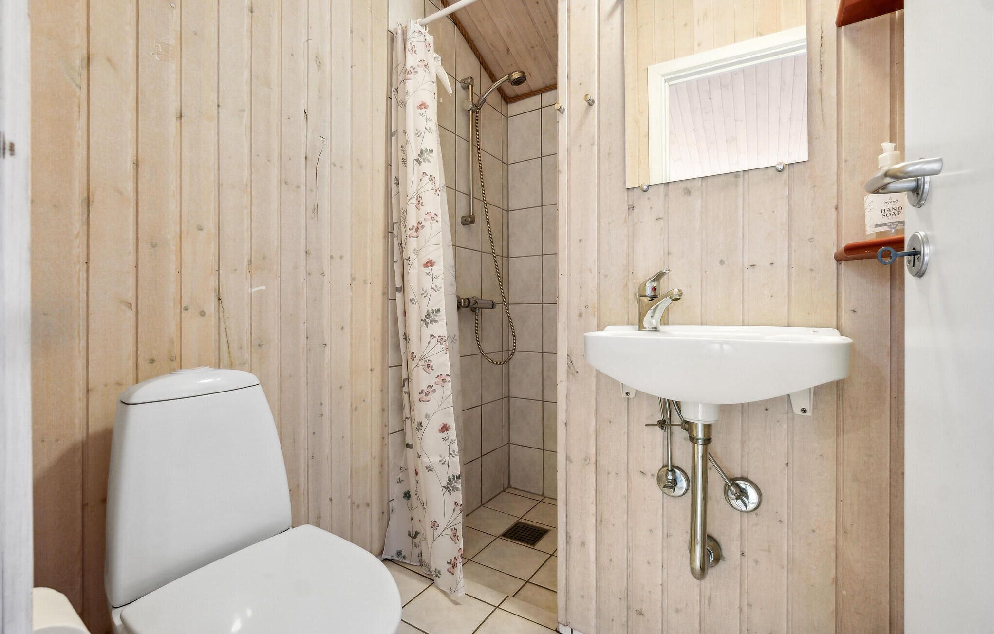 A small bathroom with a toilet, a shower, and a sink.
