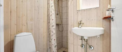 A small bathroom with a toilet, a shower, and a sink.
