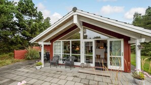 A house with a covered patio, a dining area with chairs, and a view of the interior through large windows. - Beach front home in Hurup Thy with WiFi (Hurup Thy)