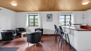 Ein modernes Interieur mit Holzboden, einer Essecke mit Barhocker und zwei mit Vorhängen versehenen Fenstern.