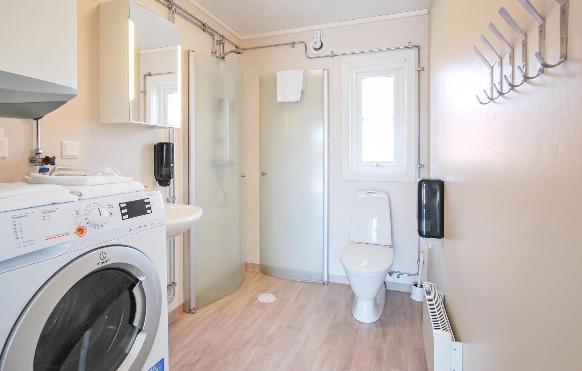 Un baño moderno y funcional con lavadora, inodoro y ducha.
