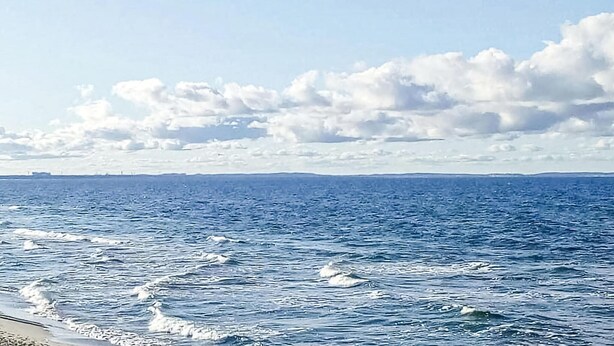 A view of the ocean with waves and a distant shoreline.