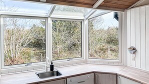 Una cocina con lavavajillas integrado, un lavabo y una ventana con vistas a un paisaje natural.