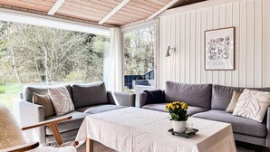 Una habitación acogedora con un sofá gris, una mesita con un florero y un cuadro en la pared.