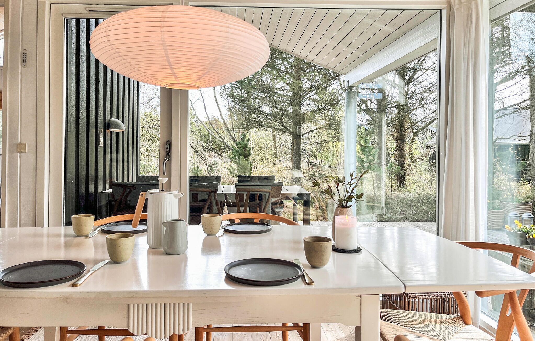 Un espace repas avec une table blanche, des chaises et un luminaire suspendu.