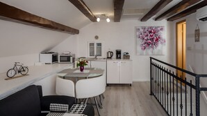A modern kitchen with white cabinets, a dining table, and a coffee maker. - Old Town Charming Nest (Dubrovnik)