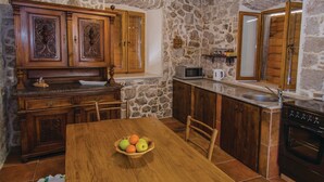 A kitchen with wooden cabinets, a stone wall, a microwave, and a sink. - Holiday Home Stari Zoganj (Orebic)