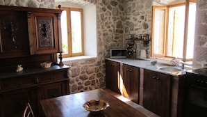 A kitchen with stone walls, wooden cabinets, a microwave, and a sink. - Holiday Home Stari Zoganj (Orebic)