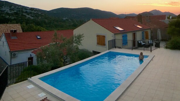 A swimming pool with a view of houses and mountains in the background. - Holiday Home Stari Zoganj (Orebic)