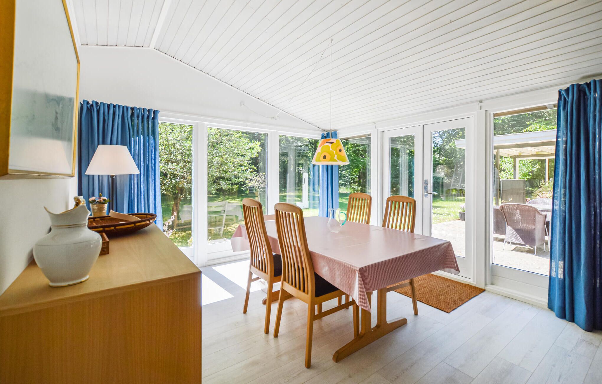 Un coin repas avec une table et des chaises, une lampe et un vase posés sur un comptoir en bois.