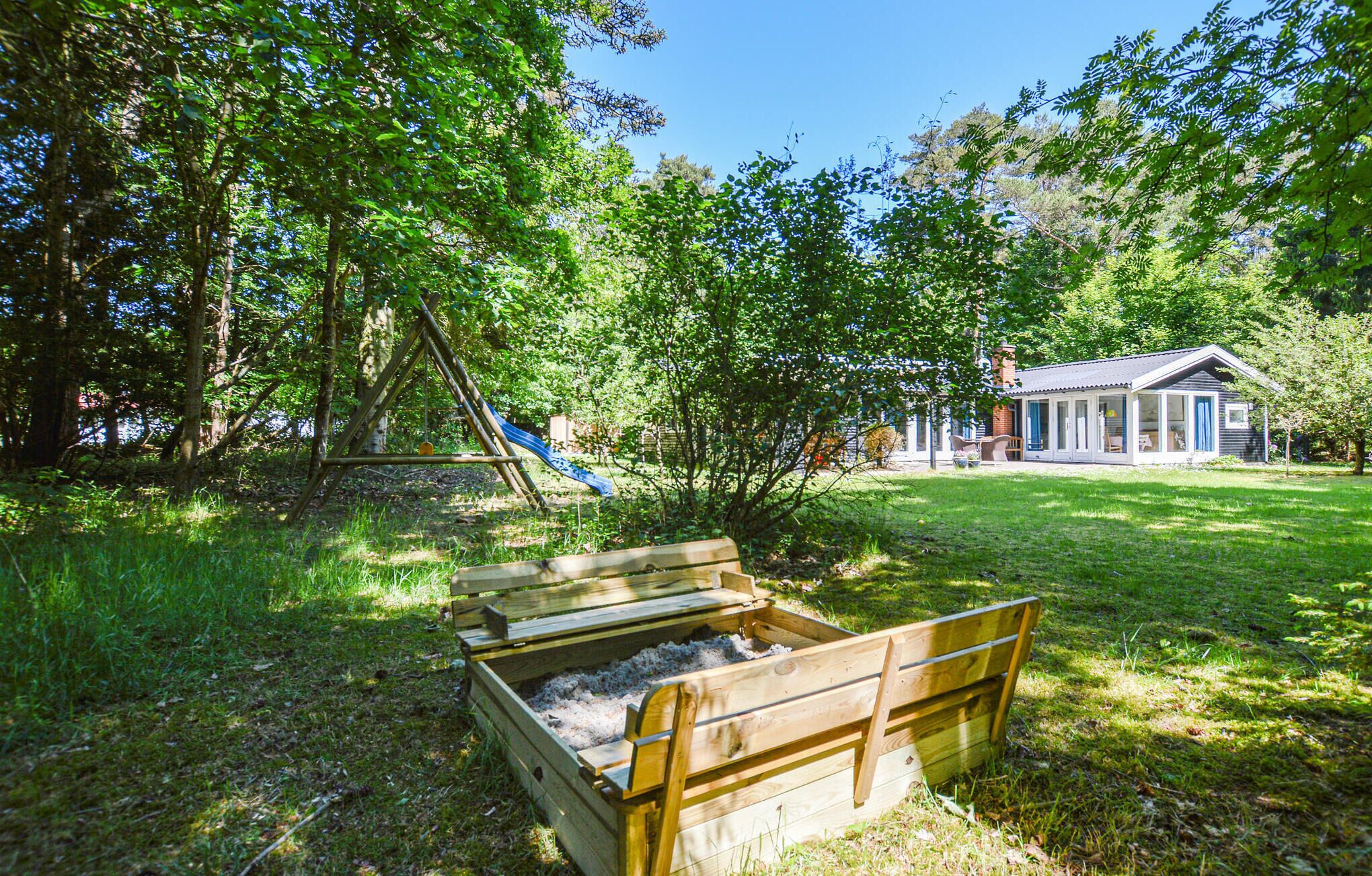 A wooden play structure with a slide, a small shed, and a grassy yard.