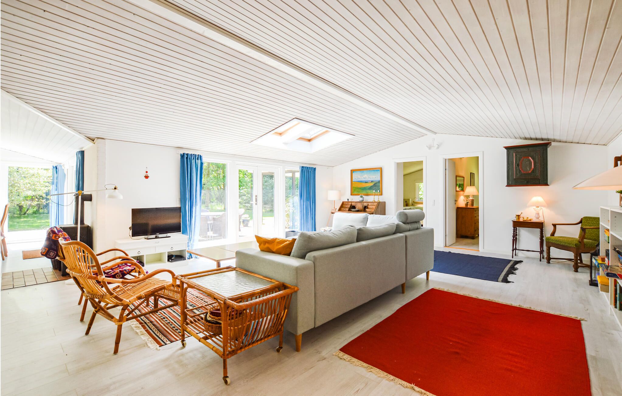 Ein geräumiges Wohnzimmer mit Sofa, Sesseln, Fernseher und Kamin.