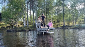 A wooden dock extending over a calm river, surrounded by trees. - Overwater Hut Kuusamo (Kuusamo)