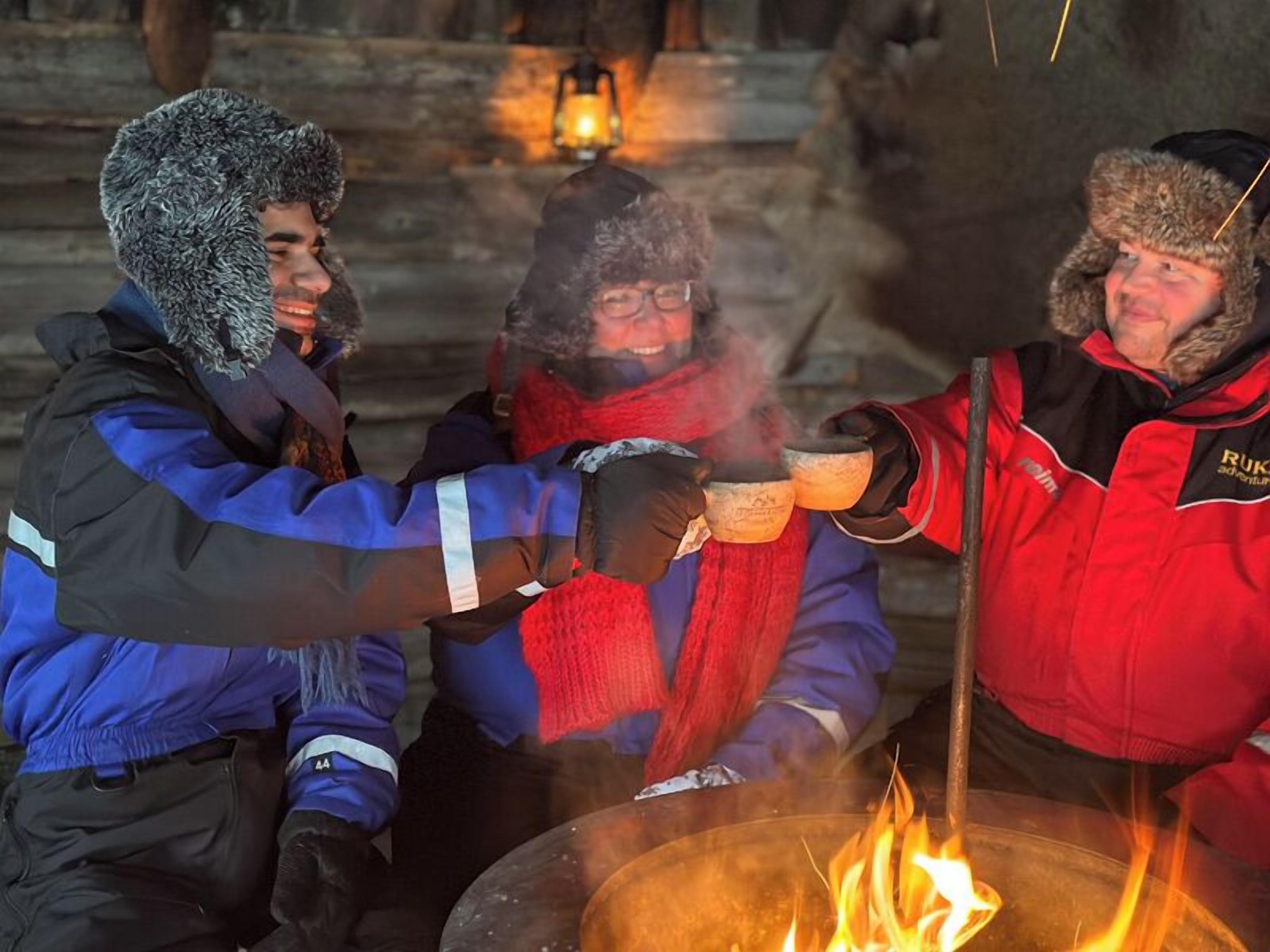 Un grupo de personas alrededor de una fogata, vestidas con ropa de invierno, lo que sugiere un ambiente frío.