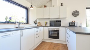 Une cuisine moderne avec des meubles blancs, un four encastré, un four à micro-ondes et un évier.