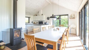 Une cuisine moderne avec des meubles blancs, un îlot central et une grande table à manger entourée de chaises.