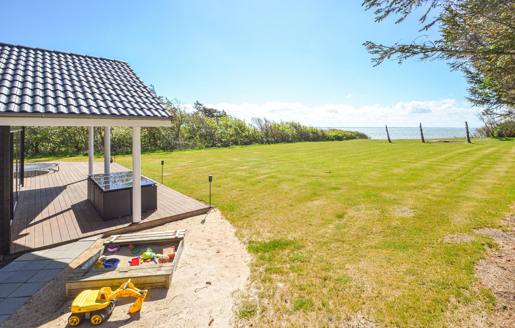 A covered patio area with a wooden deck, a barbecue grill, and a play area with toys.