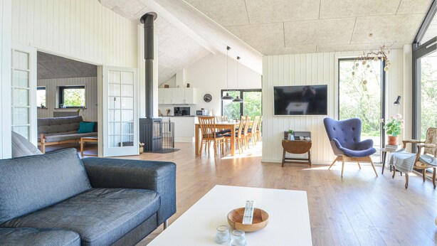 Un grand espace de vie comprenant un canapé, une table basse et un téléviseur. Il y a également un coin cuisine avec une table à manger et des chaises.