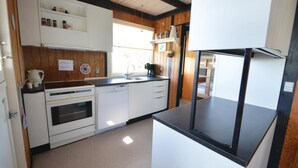 Une cuisine compacte avec des meubles blancs, un four encastré, un lave-vaisselle et un plan de travail noir.