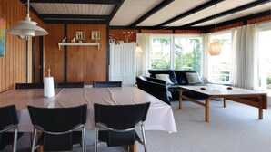 Un coin repas comprenant une table ronde, des chaises noires, un canapé et un banc en bois.