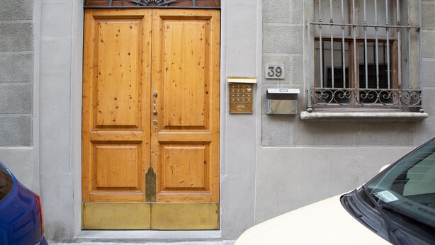 Una puerta doble de madera con un llamador de bronce, un buzón y una ventana con barrotes.