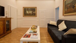 Una sala de estar con una mesa blanca, un sofá negro y un cuadro en la pared.