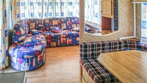 A cozy RV interior with a sectional sofa, a plaid bench, and a wooden table.