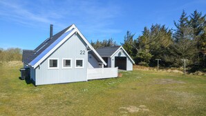 A small, single-story building with a sloped roof, numbered 22, featuring a garage and a covered porch area. - 3 bedroom awesome home in Thisted (Thisted)