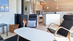 A cozy living area with a fireplace, a kitchen, and a dining table. - 3 bedroom awesome home in Thisted (Thisted)