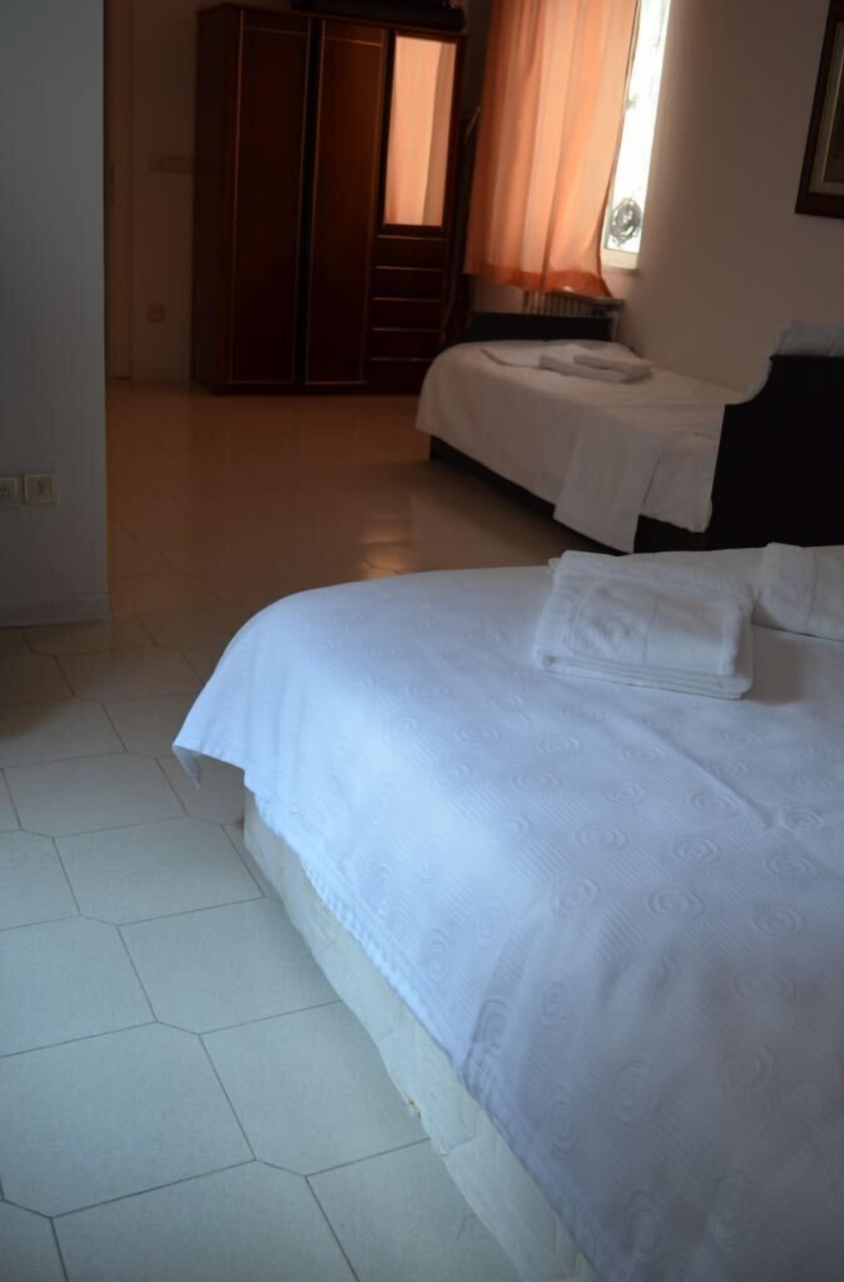 A hotel room with a large bed, a smaller bed, and a wardrobe.