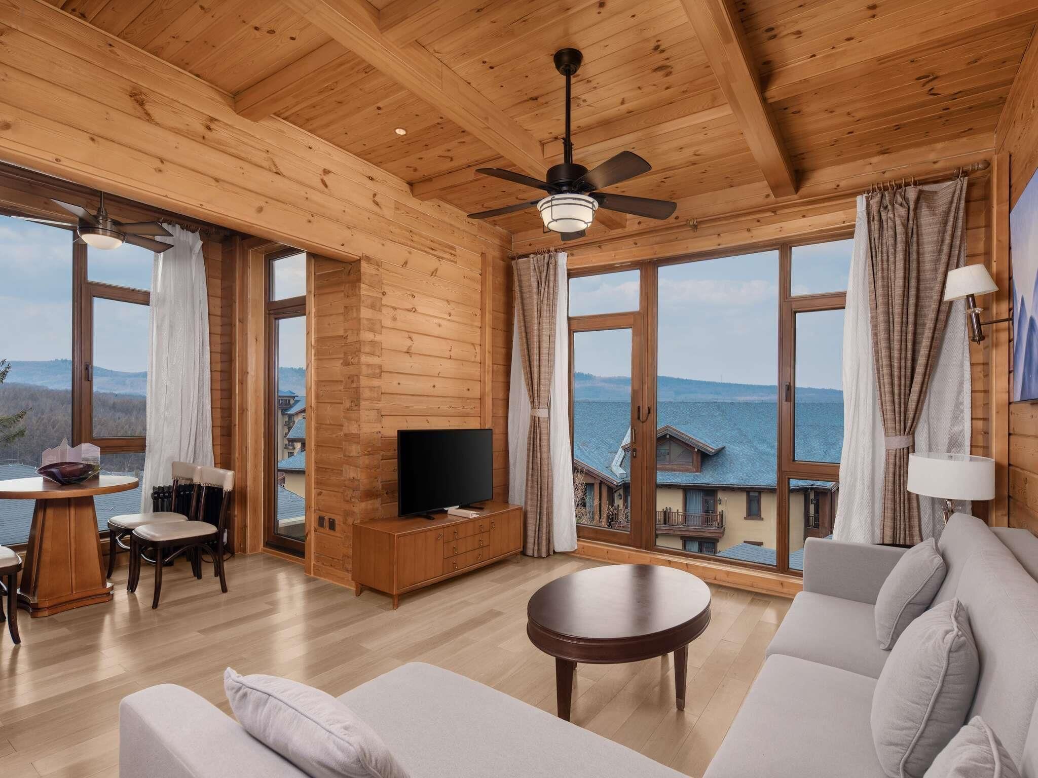 Une cabane en bois spacieuse, dotée d’un grand téléviseur, de sièges confortables et offrant une vue magnifique sur le lac.