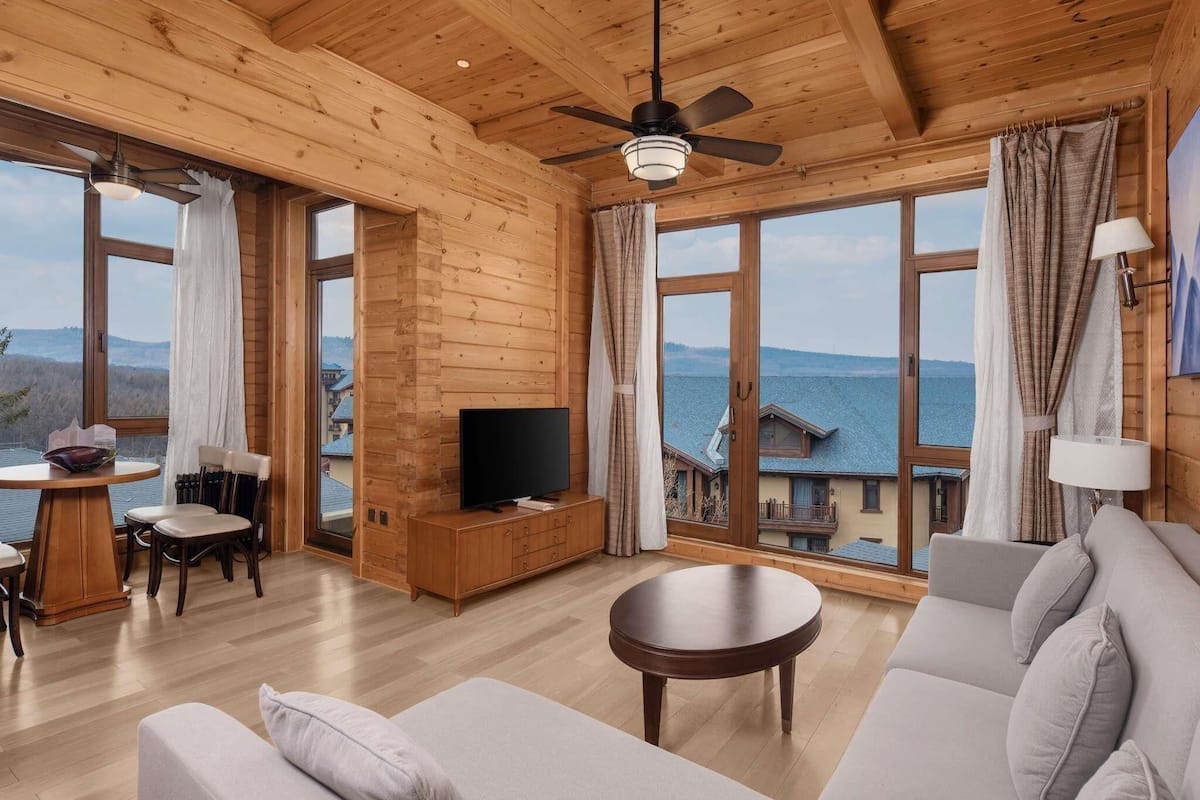A spacious wooden cabin with a large TV, comfortable seating, and a scenic lake view.