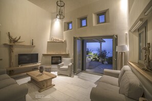 Una sala de estar moderna con chimenea, asientos cómodos, televisión y vistas al exterior.