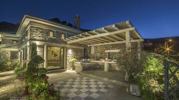 A stone house with a covered patio, a stone tower, and a checkered floor.