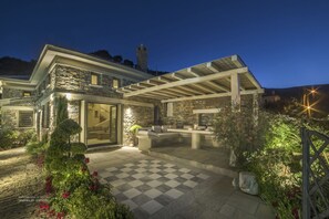 Une maison en pierre dotée d’un patio couvert, d’une tour en pierre et d’un sol à carreaux.