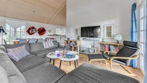 Ein geräumiges Wohnzimmer mit einem großen grauen Sofa, einem Couchtisch und einem Bücherregal.