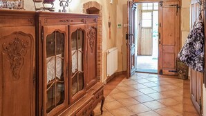 Een gang met een houten kast met glazen deuren, een radiator en een houten deur die naar buiten leidt.