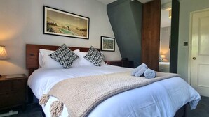 A neatly made bed with patterned pillows, a throw blanket, and a lamp on the nightstand.