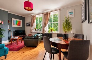 A modern living room with a television, sofa, and dining area. - Beautiful Highgate 2-Bed Apartment | Sunny Roof Terrace (London)
