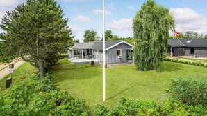 A two-story house with a covered patio and a flag. - Lovely home in Juelsminde with kitchen (Juelsminde)