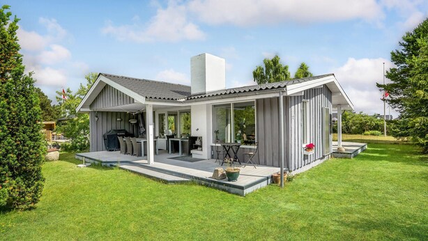 A modern house with a covered patio, outdoor seating, and a barbecue area. - Lovely home in Juelsminde with kitchen (Juelsminde)