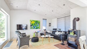 A modern living room with a fireplace, a sofa, a TV, and artwork on the walls. - Lovely home in Juelsminde with kitchen (Juelsminde)
