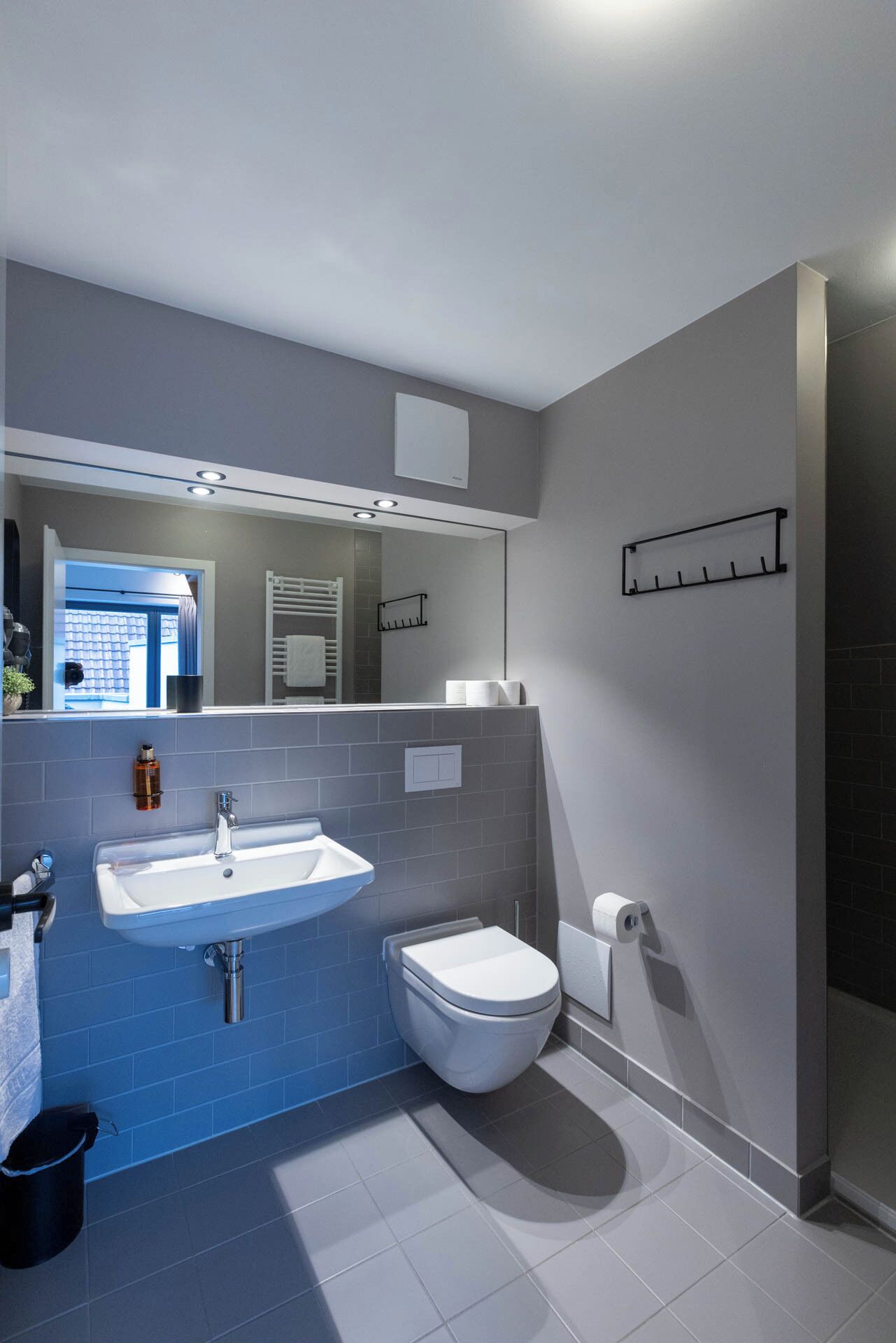 Un baño moderno con lavamanos blanco, inodoro y zona de ducha.
