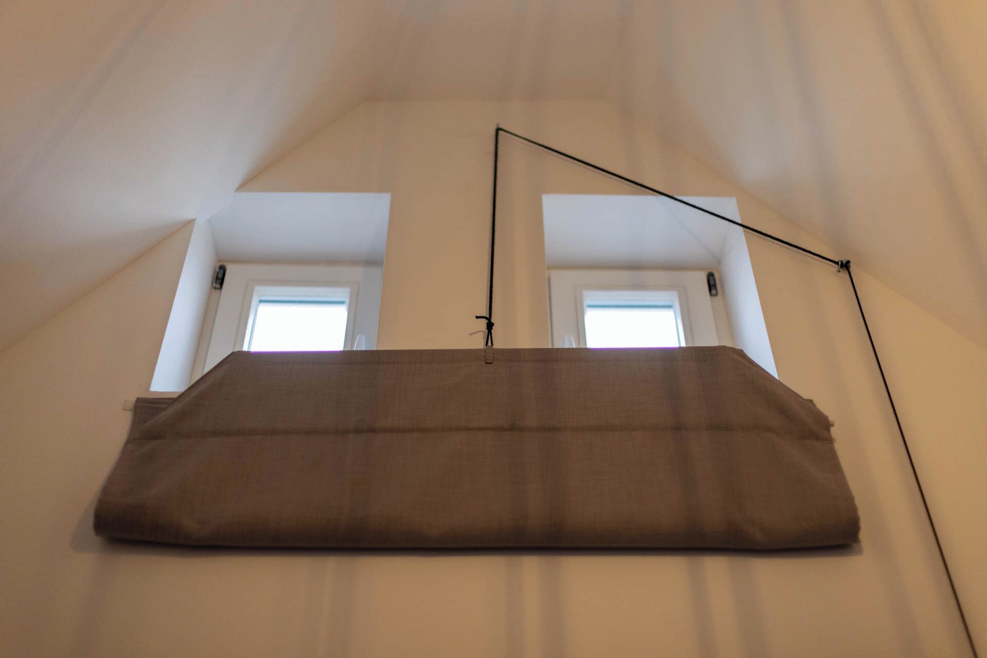 Una habitación con techo alto y tejado inclinado, que cuenta con un ventanal y una puerta.