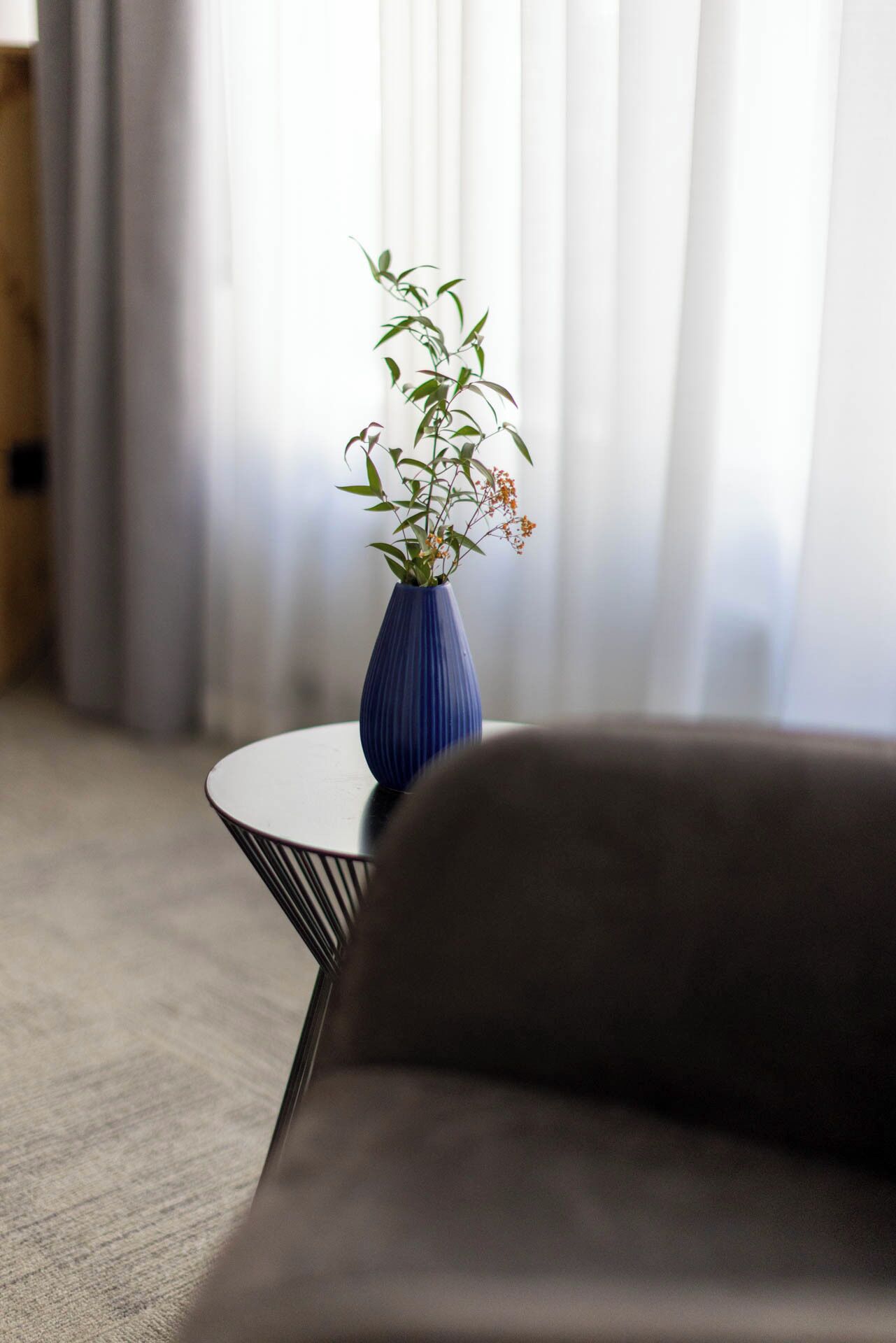 Una habitación con una mesa redonda, un jarrón azul con una planta y un sofá.